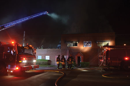 (4) Members get a handline into position on the roof of a one-story setback to operate into the second floor. The fire originated in the second-floor roof space.