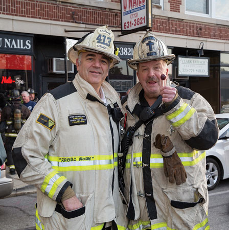 (2) Chicago (IL) Fire Department Chaplains Rabbi Moshe Wolf (left) and Father Tom Mulcrone (right) at the scene of a multiple-alarm lumberyard fire. Rabbi Moshe is known for “breaking the ice” as he visits and blesses his firefighters by handing out lollipops. (Photo by Gordon Nord.)