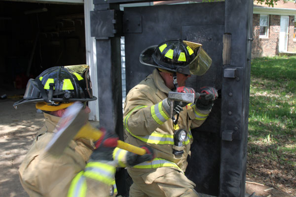 Firefighters perform forcible entry on a training prop.