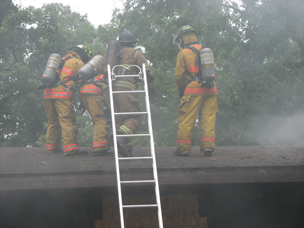 Firefighters operating on the roof at a fire scene.