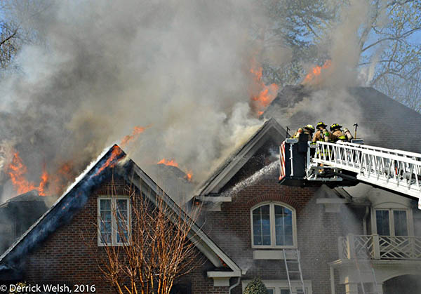 Firefighters apply water to a large fire in a single-story home in Fairfax County, Virginia.