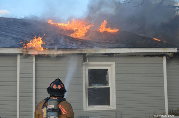 A firefighter confronts fire coming from the roof and eaves in North Carolina.