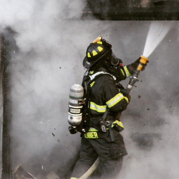 Firefighter in full protective gear and on air directing a hoseline