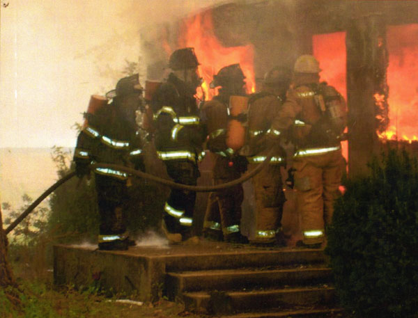 A string of firefighters holding an attack line at the scene of a structure fire. Perhaps not the optimal deployment of fireground resources.