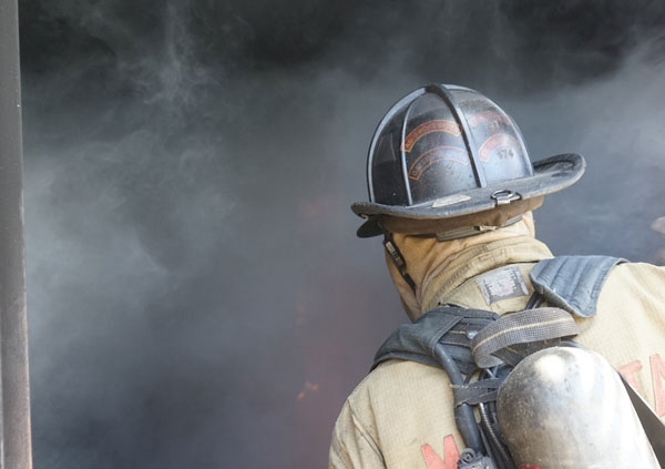 A firefighter proceeds into a smoky compartment.