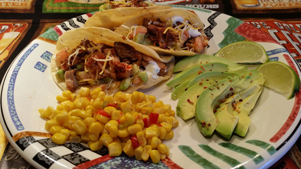 Tacos on a plate with limes and avocado