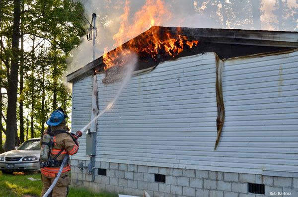 A firefighter applies water as flames show from the eaves of a home in Nash County, North Carolina.