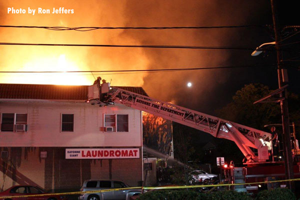 Firefighters in a tower ladder bucket as flames roar in the background in Bayonne, New Jersey.