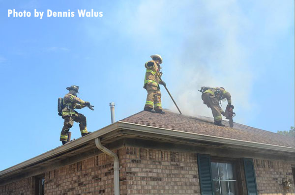 Firefighters perform roof work at a house fire in Warren, Michigan.