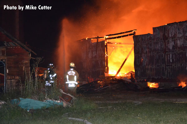 Firefighters operating with a hose stream at a barn fire in Medina, Wisconsin.