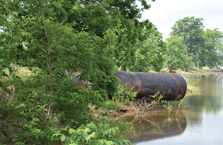 <b>(3)</b> Near Brookshire, Texas, floodwaters forced this 10-foot culvert downstream and damaged the road over it.