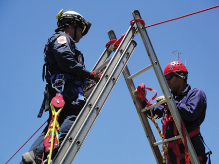 (6) Rescuers from Puerto Rico Metro Two are using short ropes as guy lines to stabilize ladder movement.