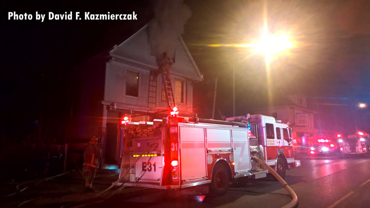 Apparatus outside a fire in Buffalo, New York, with a firefighter scaling a ground ladder.