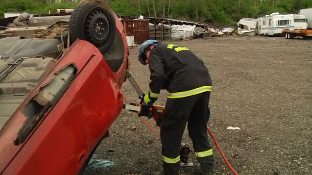 A rescuer uses extrication tools to begin the cut.