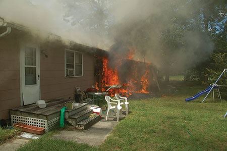 (4) A view of side C showing fire in an enclosed porch. Smoke from the eaves indicate extension to the attic <i>(Photos 4-5 by Billy Adkins.) </i>“></td>
</tr>
<tr>
<td align=