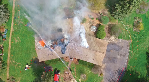 (2) Attack on an attic fire during a training burn. This positioning gives the incident commander the ability to see that the water is not hitting the seat of the fire and is pouring into the backyard of the home. This becomes a tool to make fireground operations more efficient. (Photo by Aaron Harris.)