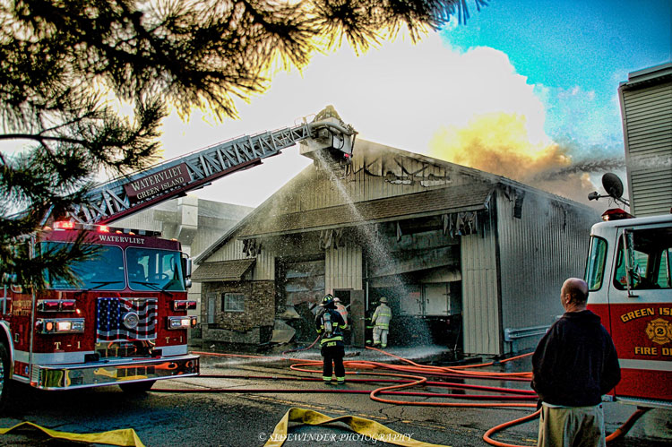 Firefighters work at the scene of a fire in an auto body shop.