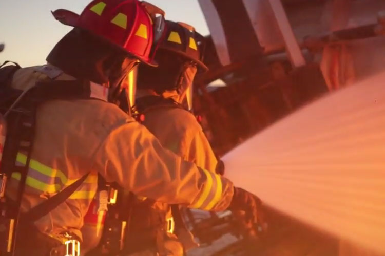 Firefighters operate a hose stream at a fire.