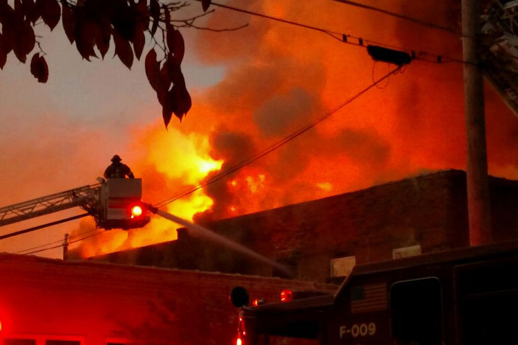 A firefighter in a tower ladder bucket pours water onto a three-alarm fire in Chattanooga, Tennessee.