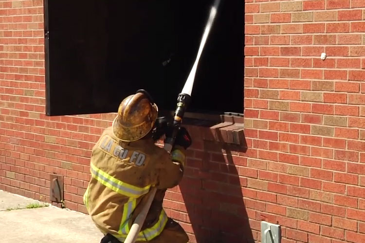 Firefighter applying water through a window