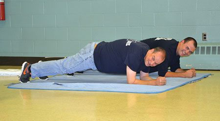 (3) LFC Battalion Chief Scott Miles (front) and Firefighter Tyler Miles perform the plank pose. 