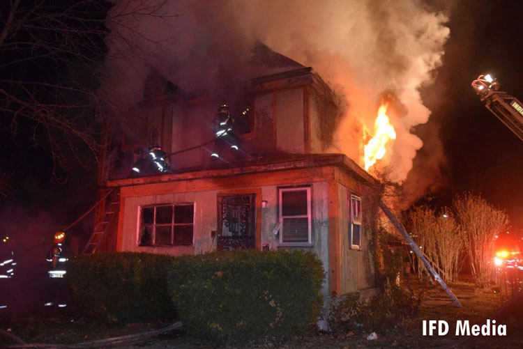 Indianapolis firefighters operate a hoseline at the scene of a residential fire.