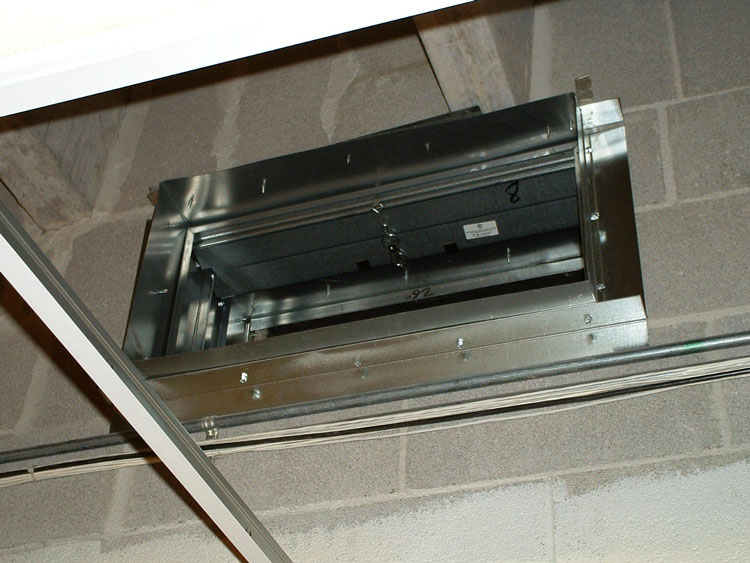 A fire damper unit that has been installed in a two-hour-rated masonry wall.