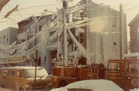 (4) These two structural carcasses collapsed after the ice melted. The weight of ice on both of these buildings and the power lines presented a double threat. In such a situation, cut off the power from a remote location and maintain collapse zones until the building comes down, whether on its own or with the help of a demolition company. These apparatus should have been moved out of the way, too. (Photo by Ron Jeffers.)