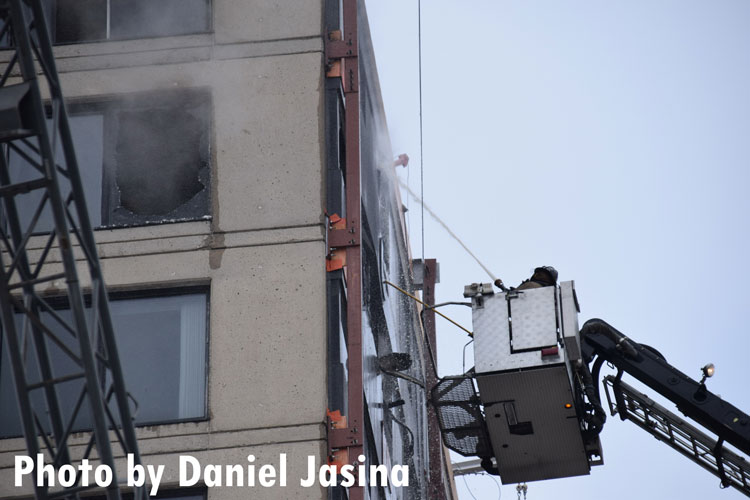 A firefighter applies water from the bucket of a tower ladder.