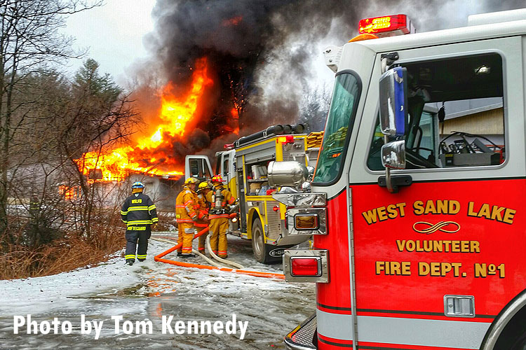 Firefighters and apparatus at the scene of a fully involved structure fire