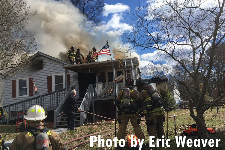 Firefighters work the roof at a house fire in North Carolina.