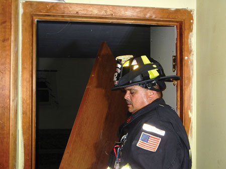 (7) Grasping the door knob, carry the door from the area, allowing unobstructed entry into the room.