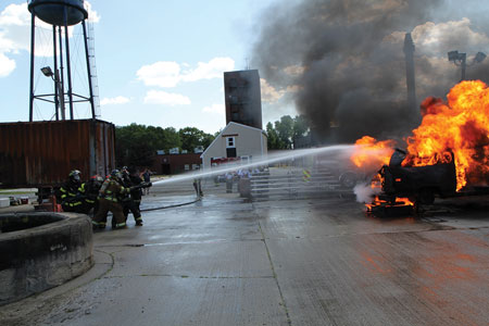 (1) Students perform a car fire evolution at Camp Fahrenheit 516. <i>(Photos by Jerry Presta.)</i>