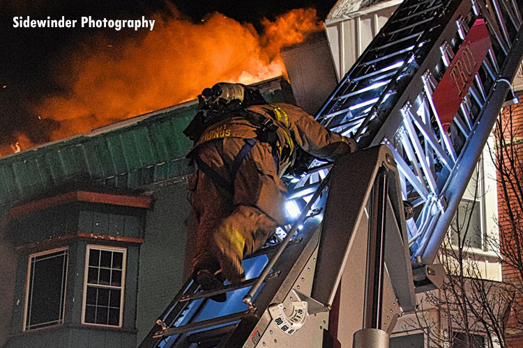 A firefighter on an aerial ladder at the scene of a massive fire in the city of Troy, New York.