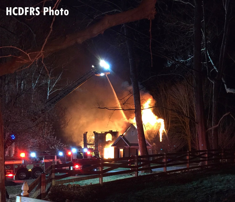 Fire apparatus with aerial device operating at house fire