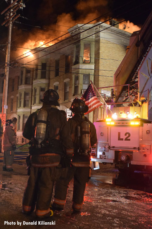 Firefighers with an American flag on a fire truck at a fire in Buffalo, New York.