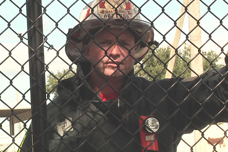 Orlando Fire District Chief Walt Lewis behind a chain link fence