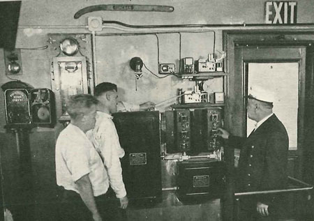 (2) Fire Alarm Telegraph and the A.D.T. Section of the School. Captain Cashman Making a Test.