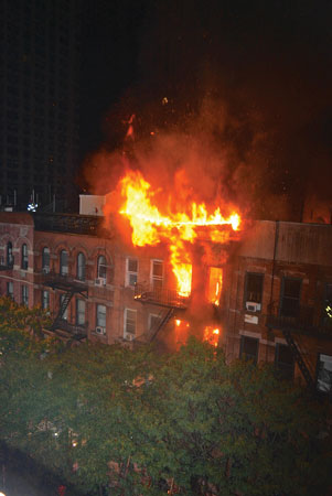 (3) Fire has control of the entire exposure 4 top-floor apartment and is most likely affecting the supports on the roof on which the members are operating to make this rescue.