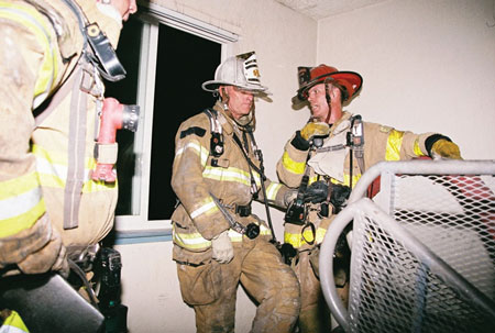 (5) The Division 3 supervisor at the same fire communicates face-to-face with a company officer in the stairwell. Notice the division supervisor is wearing full personal protective equipment and SCBA so he can enter the immediately dangerous to life or health environment for accountability or communication.