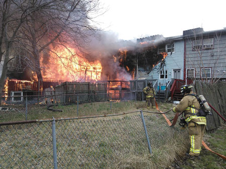 (2) The presence of wood decks, wind, and combustible siding allowed fire to bypass these masonry fire walls. <i>[Photo courtesy of Battalion Chief John Rezes, Perth Amboy (NJ) Fire Department.] </i>