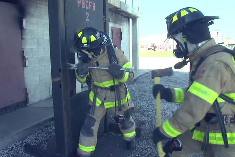 Firefighters perform forcible entry on a door prop.