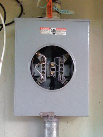 (11) “Jumper” wires bridging terminals in the meter “can” supply this house with free electricity. (Photo by James Dupre.)