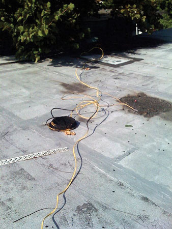 (8) Burning insulation on the Romex™ nonmetallic cable ignites the rubberized membrane roof covering. <i>[Photos 8-10 courtesy of Miami-Dade (FL) Fire Rescue.]</i> (9) The arrow indicates where the Romex™ cable is hooked over a 110-volt wire to steal electricity from the power company. (10) This Illegal connection of wires to electric service was cut by the power company for nonpayment of the electric bill. (11) “Jumper” wires bridging terminals in the meter “can” supply this house with free electricity. (Photo by James Dupre.)”></td>
</tr>
<tr>
<td align=