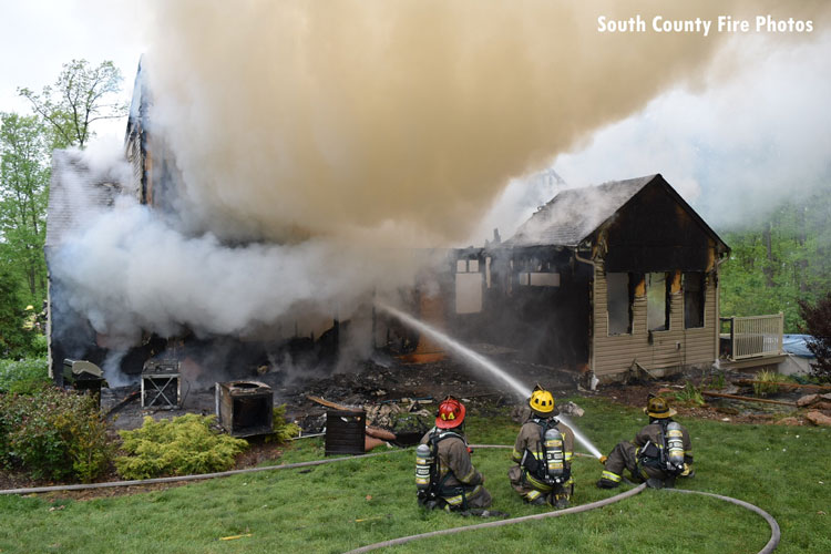 Firefighters operate a hoseline at a house fire