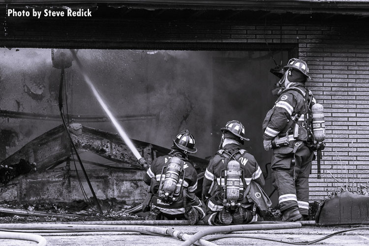 Firefighters operate at the scene of an attached garage fire