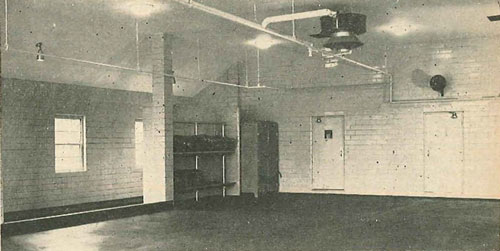 (5) Modern apparatus floor of Station 4 of the East Providence Fire Department in Rhode Island has many features. It is roomy enough to manipulate two large pieces of apparatus, has overhead heating and lighting, floor drains with special apparatus washing section at far left, hose racks next to electric hose dryer. Note two of many entrances leading from hallway and crew’s quarters into apparatus room; also public address system over door. Room has protective clothing rack (not shown).