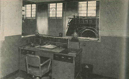 (6) Newness and dispatch, plus vision, feature new Portland, Ore., Station. Engine 22 has many features, one of which is this watch office. It is located to permit observation of apparatus floor, is well lighted and attractively furnished, with two tone tints, inlaid floor covering and colored metal furniture. Note compactness with which all radio and wire controls and instruments are mounted on desk. 