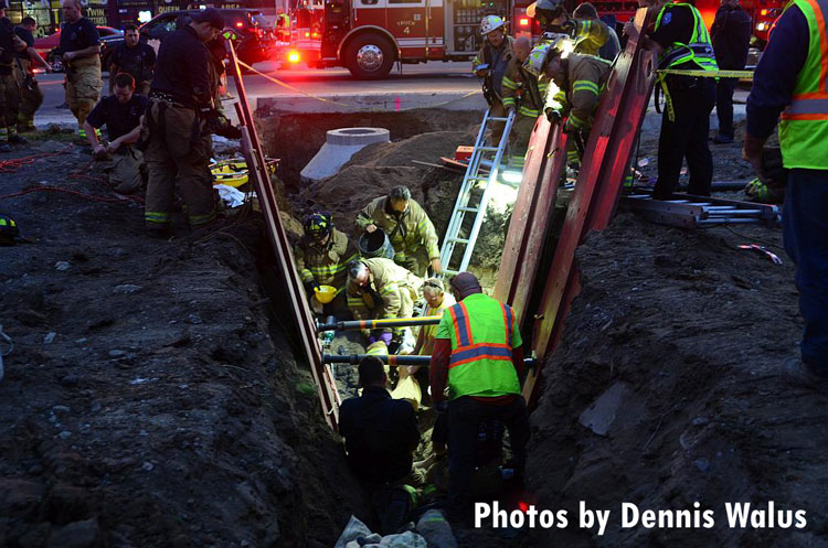 Firefighters work to rescue a man trapped in a trench