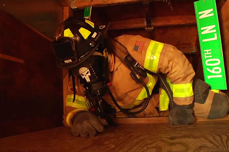 Firefighter in blacked-out face piece navigating SCBA confidence maze course